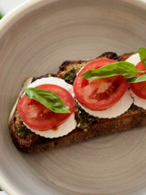 grzanka z chleba pełnoziarnistego z wegańskim pesto ricottą i pomidorami